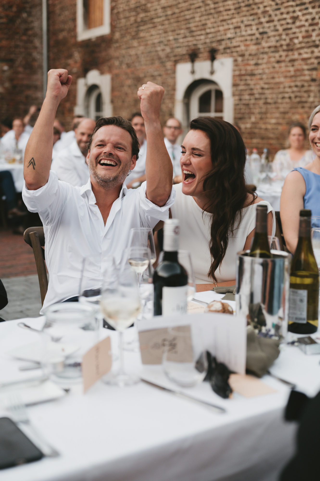 Bruidspaar geniet en viert feest tijdens het bruiloftsdiner buiten. Tijdloze en authentieke trouwfotografie door TwentyTwelve Photography