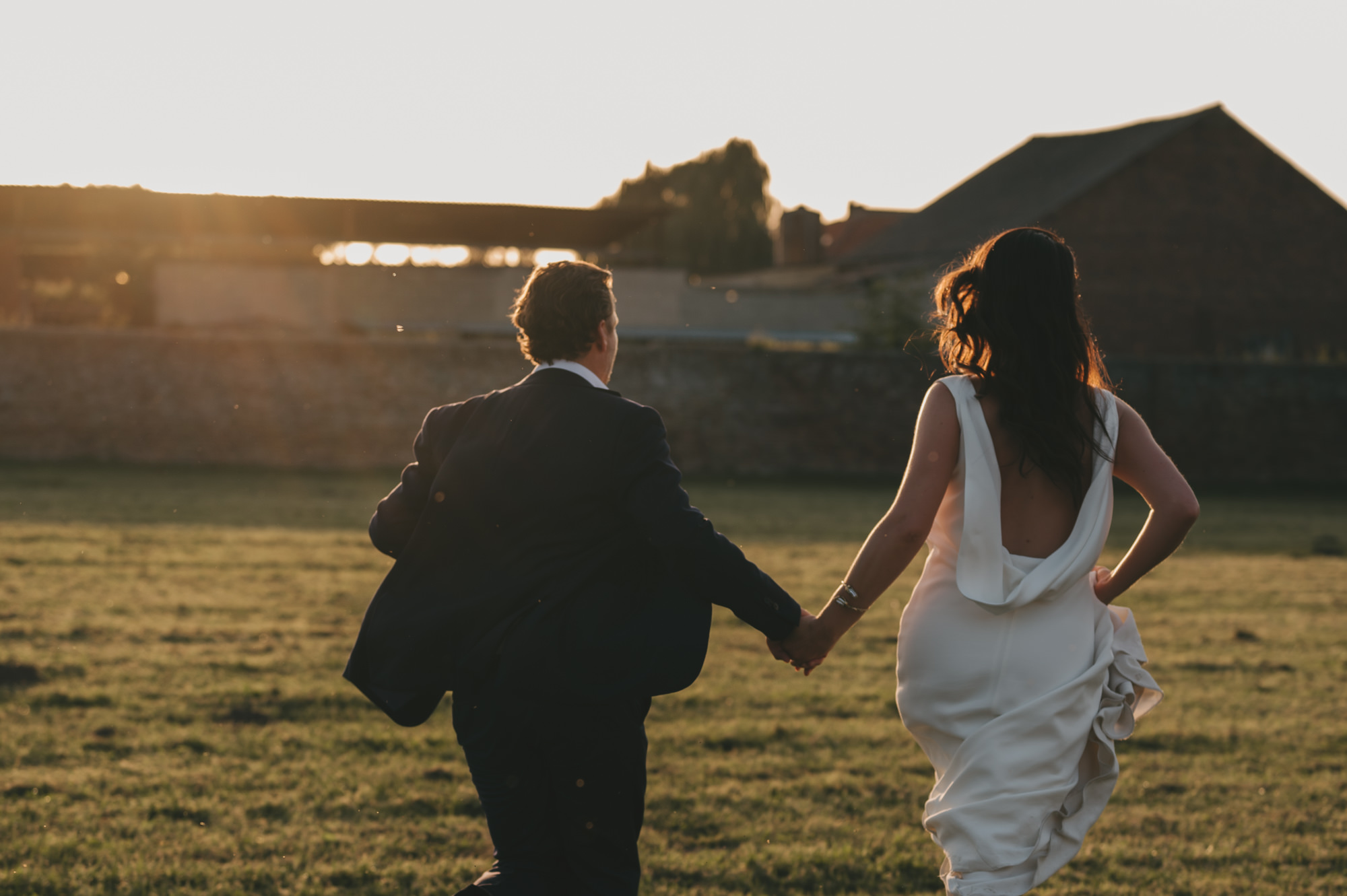 Filmische en tijdloze trouwfotografie tijdens golden hour. Het bruidspaar rent en geniet van een romantisch en spontaan moment in het warme avondlicht.