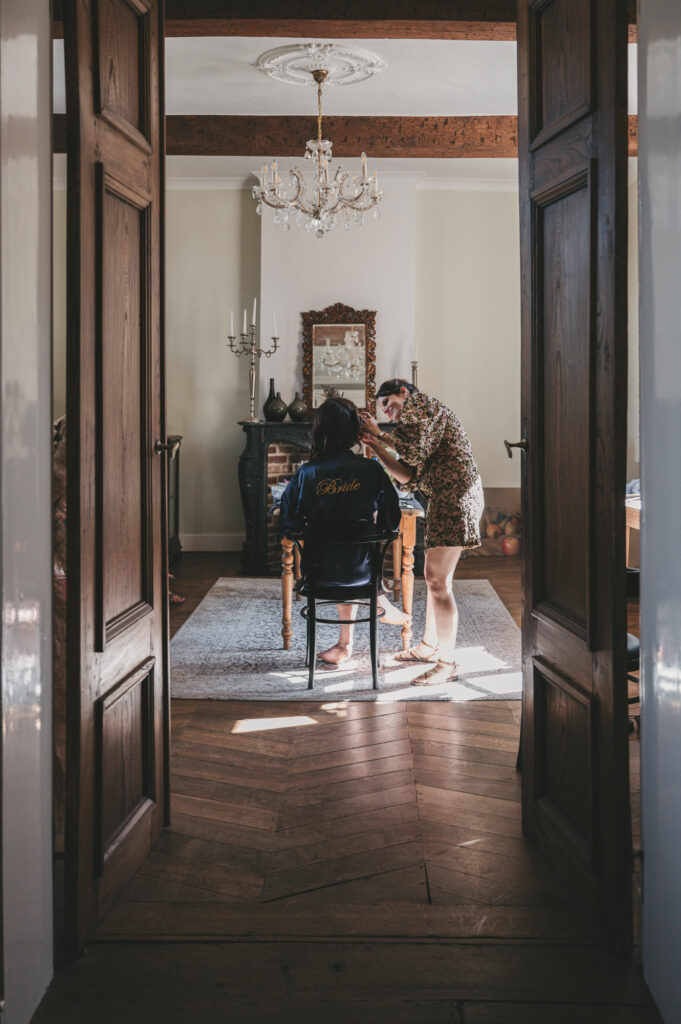 Bruid krijgt haar en make-up styling in een sfeervolle ruimte van een historisch landgoed. Tijdloze trouwfotografie door TwentyTwelve Photography