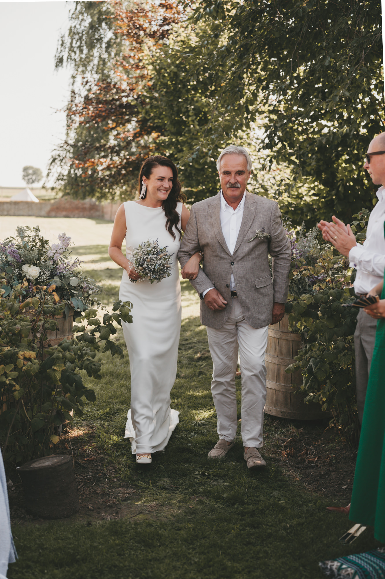 Bruid loopt gearmd met haar vader naar het altaar tijdens een romantische buitenceremonie. Tijdloze trouwfotografie door TwentyTwelve Photography