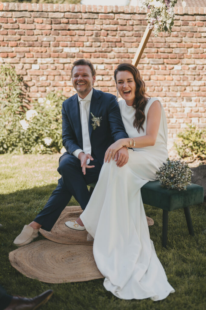 Lachend bruidspaar tijdens een ontspannen en stijlvolle bruiloftsceremonie. Tijdloze en authentieke trouwfotografie door TwentyTwelve Photography