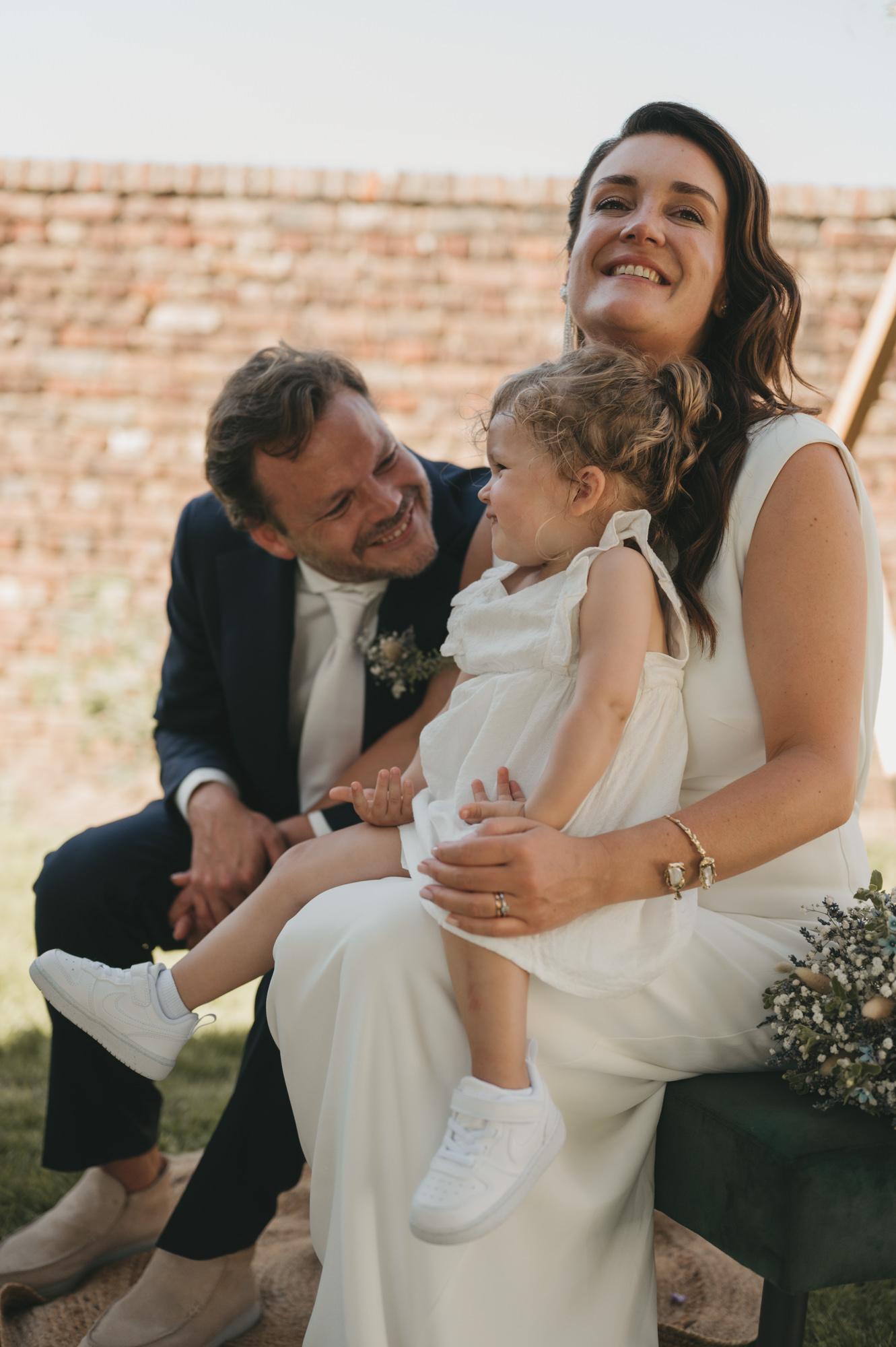 bruidspaar geniet tijdens de ceremonie samen met hun kind als bruidsmeisje