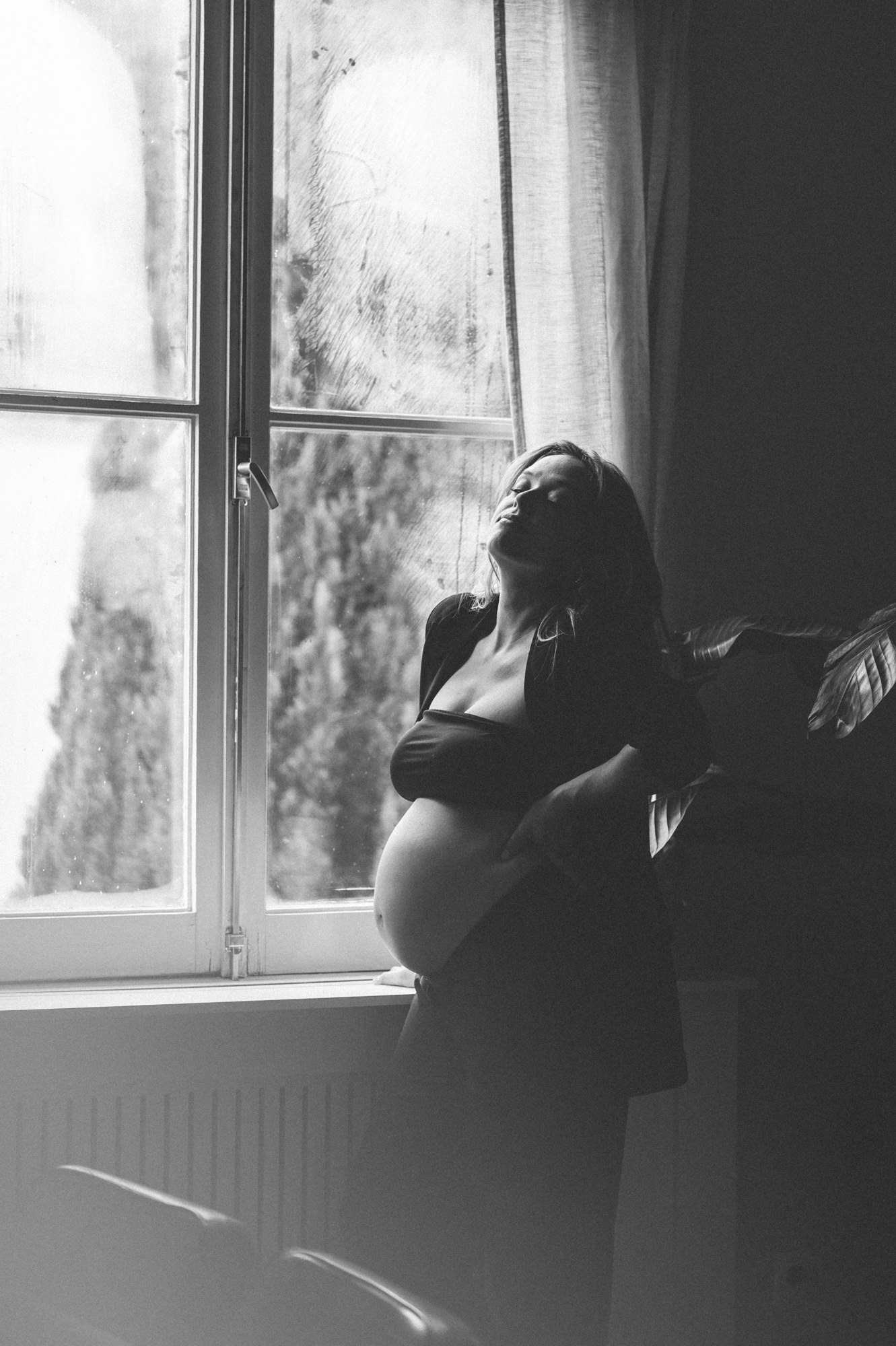 Zwangerschapsshoot Haarlem - Zwart-wit artistieke foto van een zwangere vrouw bij het raam