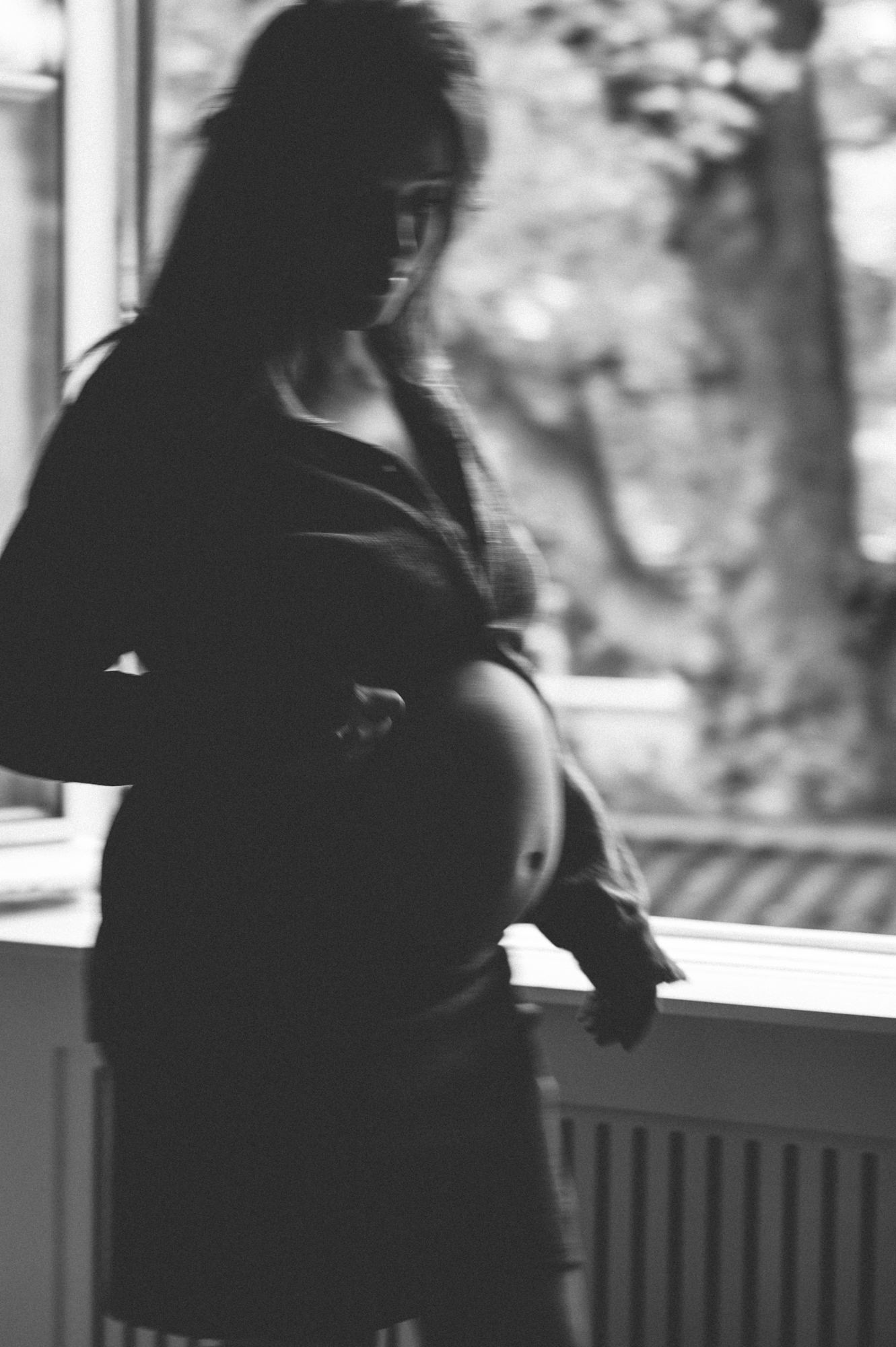 Zwangerschapsshoot Haarlem - Zwart-wit artistieke foto van een zwangere vrouw bij het raam